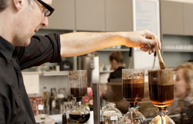Основатель Blue Bottle Coffee Джеймс Фриман готовит кофе в сифоне в одном из брю-баров компании − блог обжарщиков Torrefacto