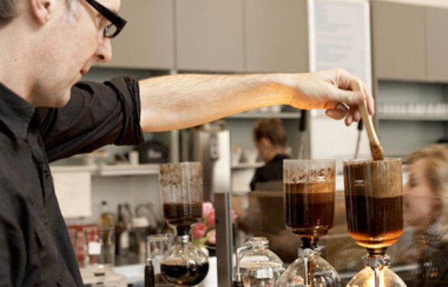 Основатель Blue Bottle Coffee Джеймс Фриман готовит кофе в сифоне в одном из брю-баров компании - блог обжарщиков Torrefacto Основатель Blue Bottle Coffee Джеймс Фриман готовит кофе в сифоне в одном из брю-баров компании - блог обжарщиков Torrefacto