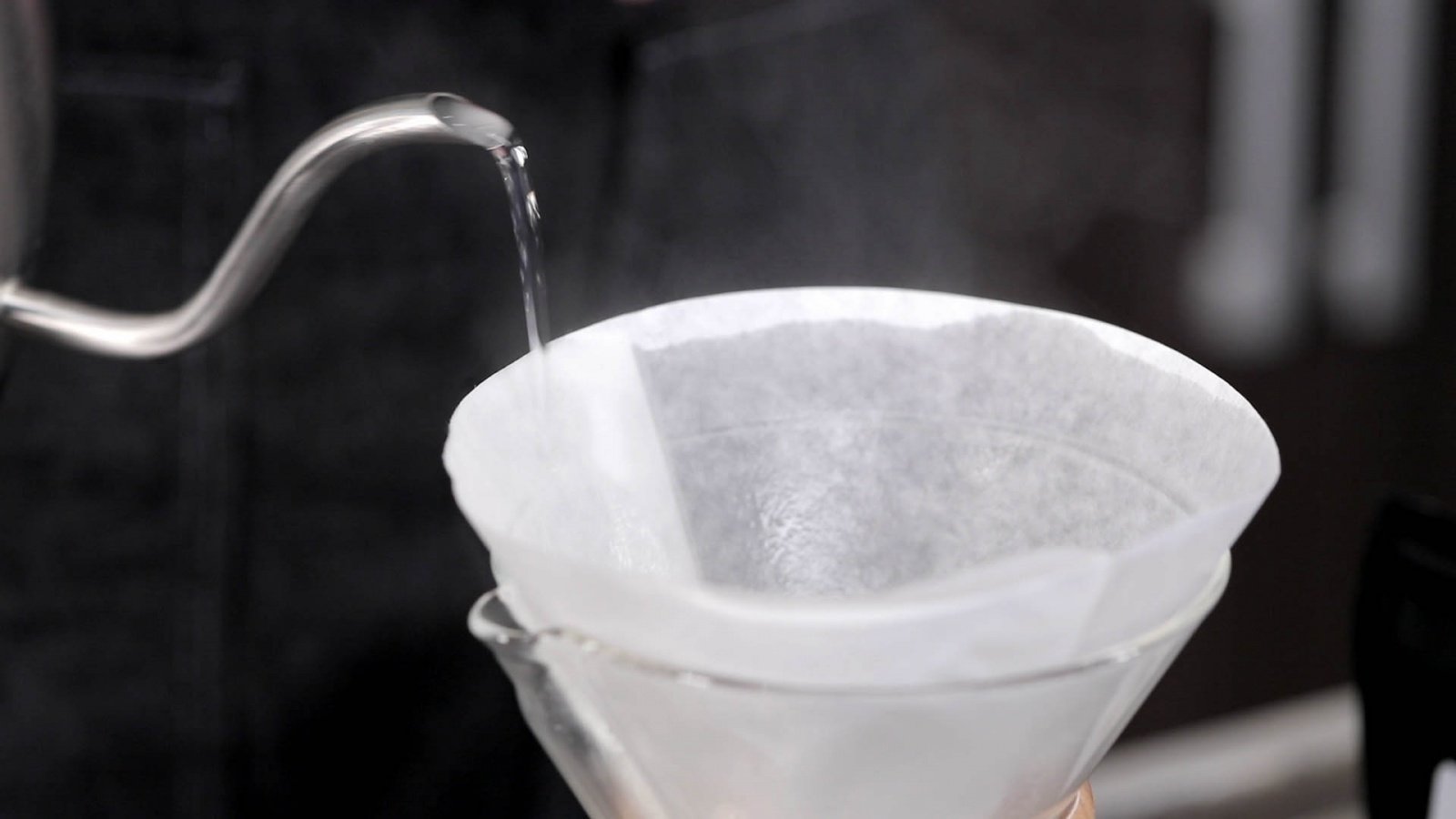 Приготовление кофе в кемексе. Шаг 5 − Обильно смочите фильтр горячей водой. Слейте воду через носик, не вынимая фильтр;